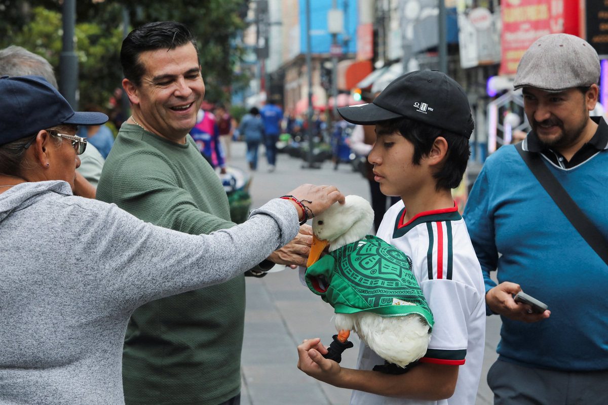 Christian Gomez holds Merlin, a duck, wearing a Mexico national football team ('El Tri') jersey that shot to fame after a chance encounter on Reforma Avenue went viral following the FIFA 2026 match between Mexico and South Africa, while people pet it in Mexico City, Mexico, June 16, 2026. REUTERS/Paola Garcia