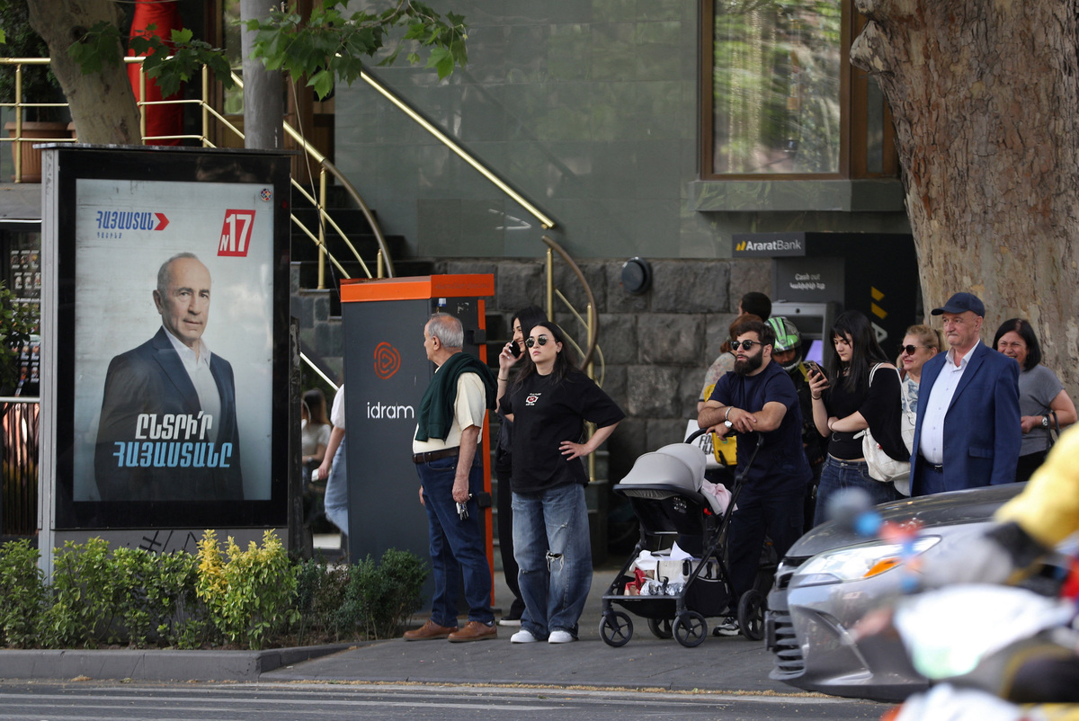 People stand in the street next to a campaign banner for the Armenia Alliance, led by Robert Kocharyan, ahead of the June 7 parliamentary election in Yerevan, Armenia June 2, 2026. Hayk Baghdasaryan/Photolure via REUTERS