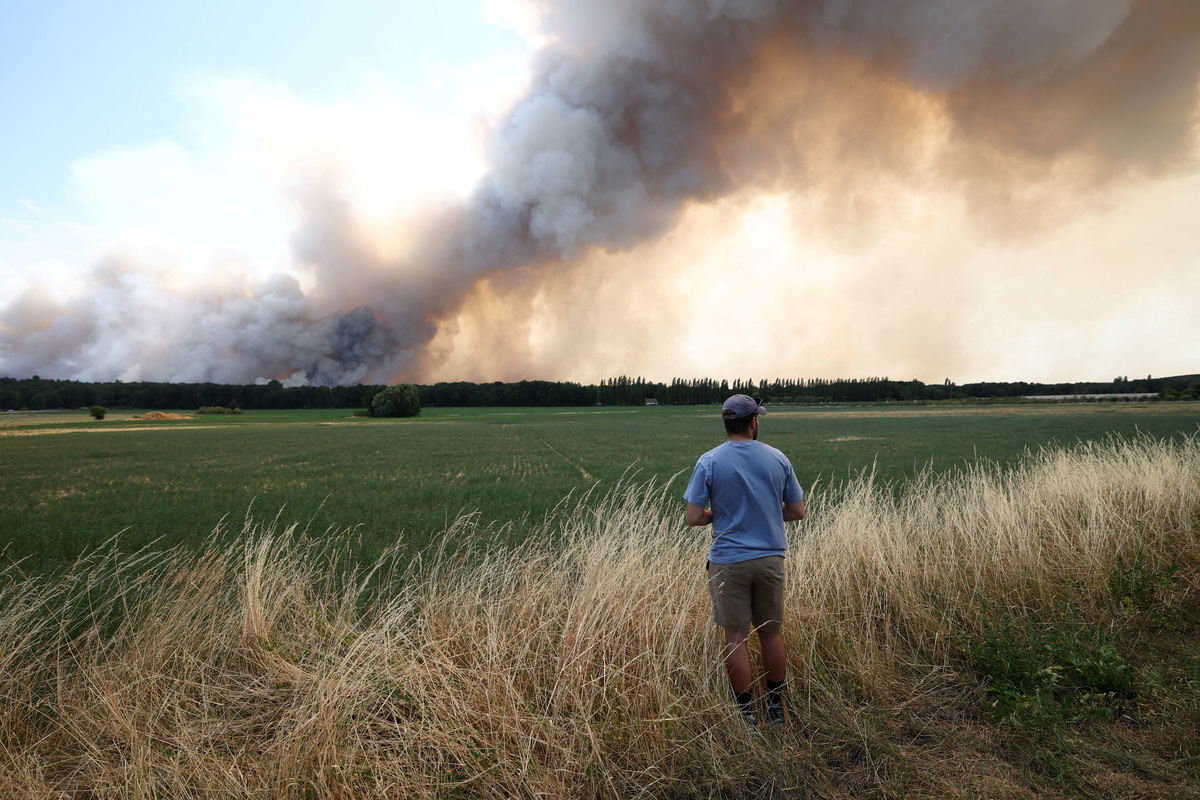 A man looks at a wildfire wich burns the Fontainebleau forest in Milly-la-Foret near Paris during a heatwave affecting large parts of France, July 13, 2026. REUTERS/Stephane Mahe