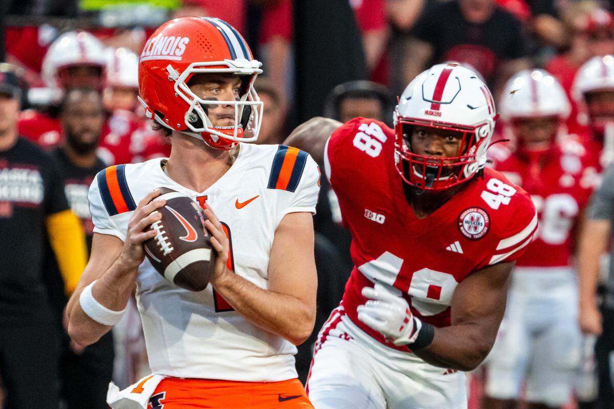 Illinois Fighting Illini quarterback Luke Altmyer drops to throw against Nebraska Cornhuskers linebacker MJ Sherman during the first quarter of Saturday’s game at Memorial Stadium.