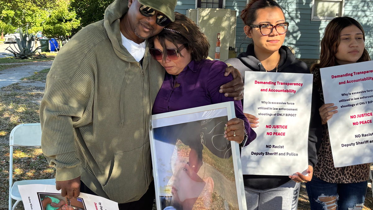 Rodney Dixon, whose son was shot and seriously injured by law enforcement officers, hugs Elizabeth Sierra, whose son was