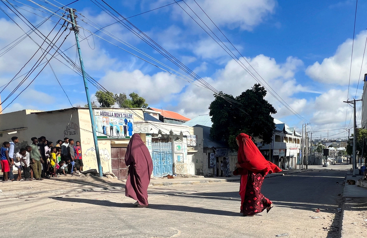 Women walk across a deserted street as people peer to watch ahead of a protest against Somalia's President Hassan Sheikh Mohamud, where opposition leaders say his term ended in mid-May, while the president and his allies say he is allowed to stay on for a year until elections are held, in Mogadishu, Somalia June 4, 2026. Picture taken with a mobile phone. REUTERS/Feisal Omar