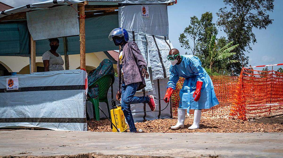 Health worker Dieudonné Sezabo, right, decontaminates the clothing of a motorcycle taxi driver who transported a patient suspected of having Ebola to the Rwampara Hospital in Ituri, eastern Democratic Republic of the Congo, on Tuesday.