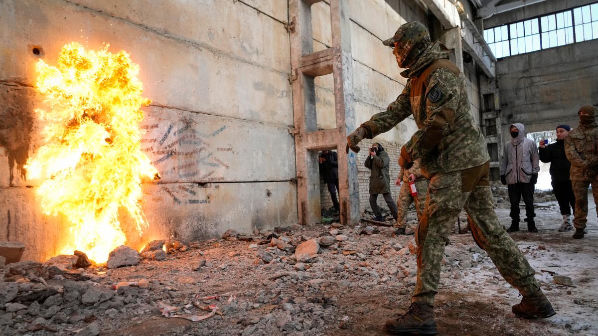 Un residente arroja una bomba molotov contra un muro durante una campaña ucraniana de entrenamiento militar, el domingo 6 de febrero de 2022, en las cercanías de Kiev, Ucrania. (AP Foto/Efrem Lukatsky)