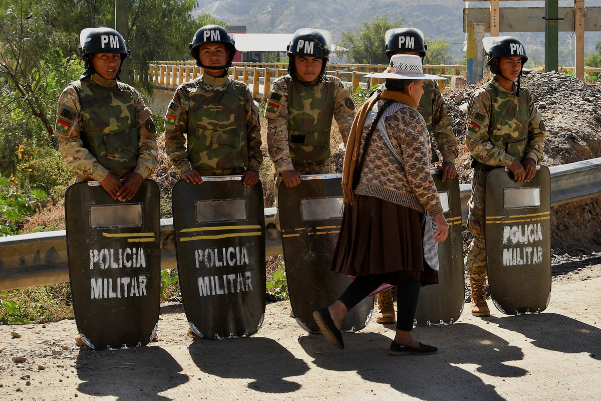 Military personnel stand in formation as they are deployed, while a woman walks past in front of them, after Bolivian President Rodrigo Paz declared a nationwide state of emergency following weeks of violence and blockades,  in Cochabamba, Bolivia, June 20, 2026. REUTERS/Patricia Pinto