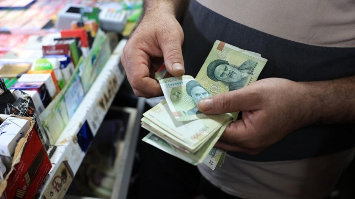 An Iranian shopkeeper counts one hundred thousand rial banknotes in his kiosk in Tehran, Iran. Photo by ABEDIN TAHERKENAREH / EPA