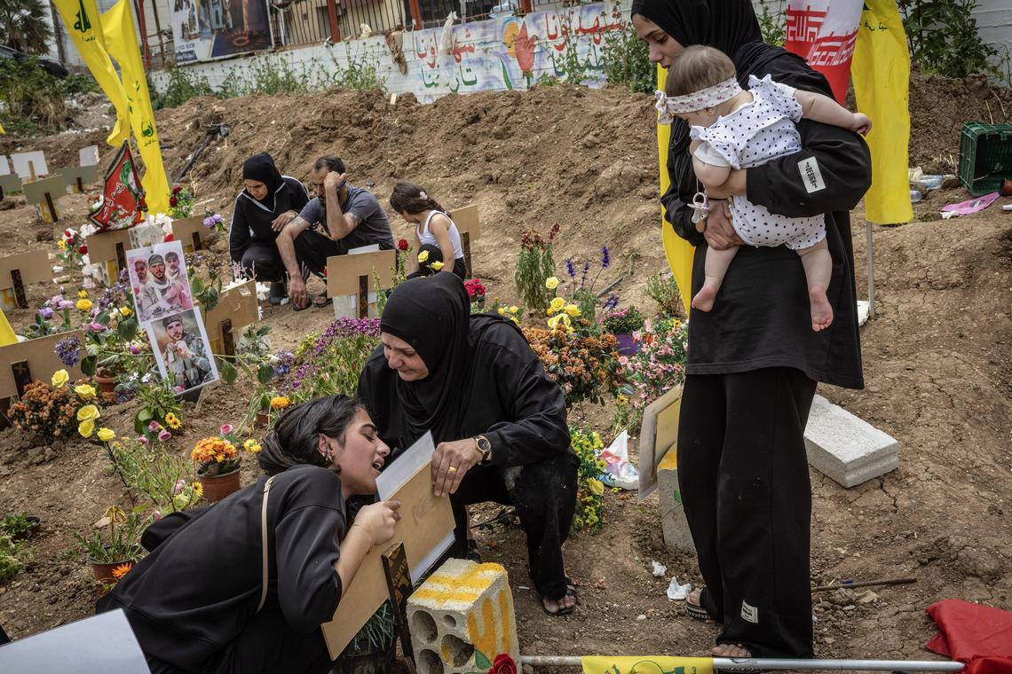Family members grieve over a temporary grave for Hussein Bourse at a cemetery in Tyre, Lebanon, April 18, 2026. Gathering at the cemetery for the first time since the ceasefire, they hope to relocate the remains to their now accessible home villages. (David Guttenfelder/The New York Times)