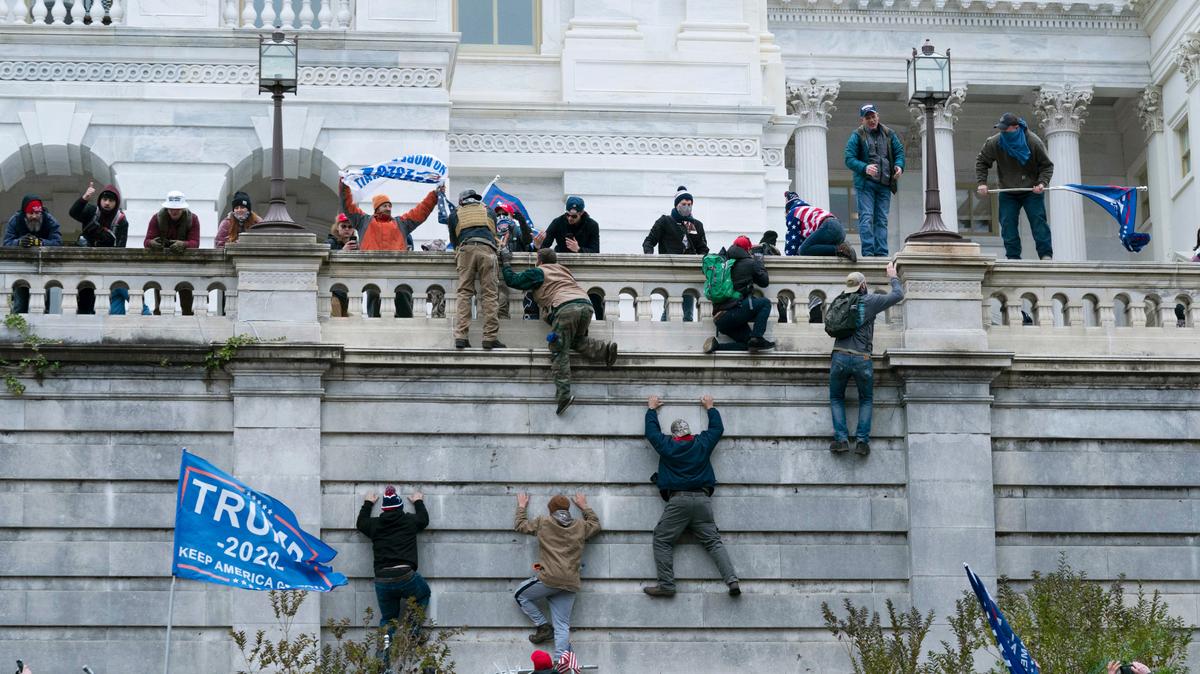Violentos seguidores del entonces presidente Donald Trump intentan escalar el muro oeste del Capitolio de EEUU, en Washington, para entrar a la fuerza al recinto legislativo, el 6 de enero de 2021. El Partido Republicano se ha negado a aprobar una comisión del Congreso que investigue el violento ataque contra el sistema democrático de Estados Unidos.