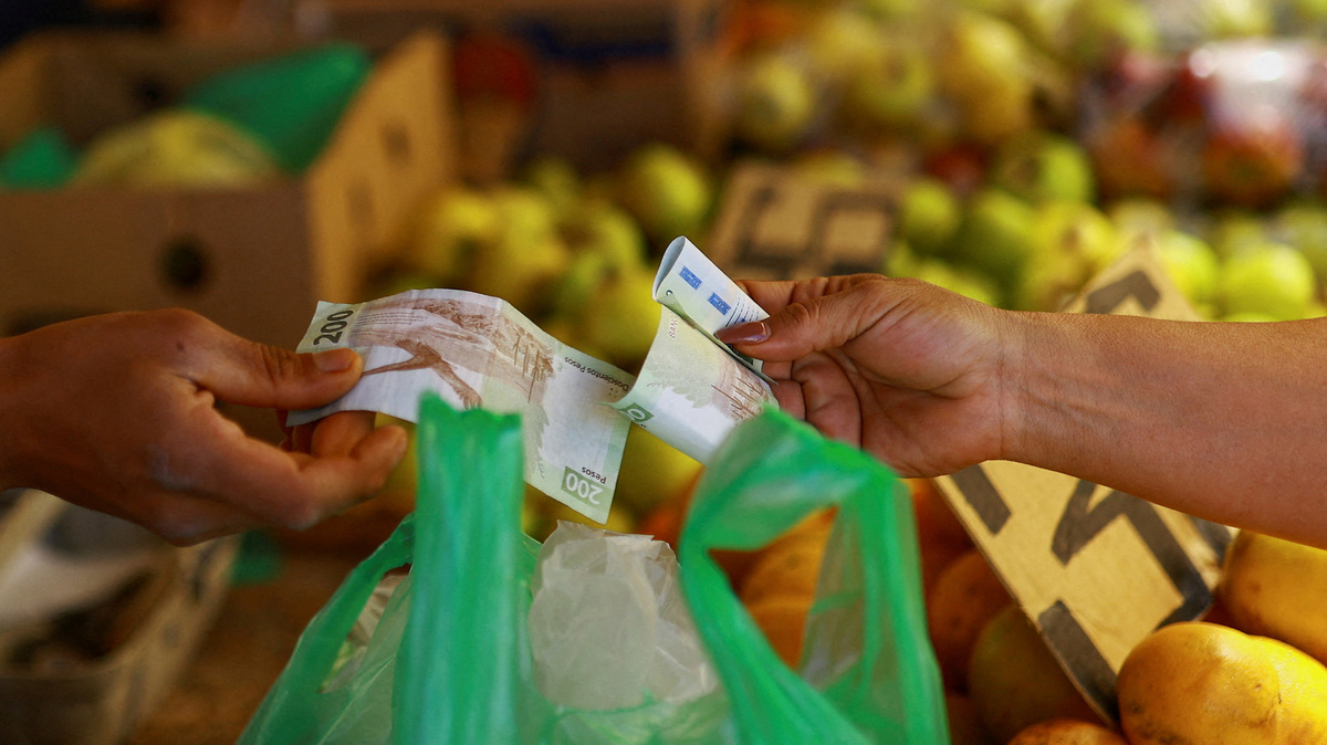 FILE PHOTO: A customer pays a vendor at a market stall in Ciudad Juarez, Mexico, April 15, 2026. REUTERS/Jose Luis Gonzalez/File Photo