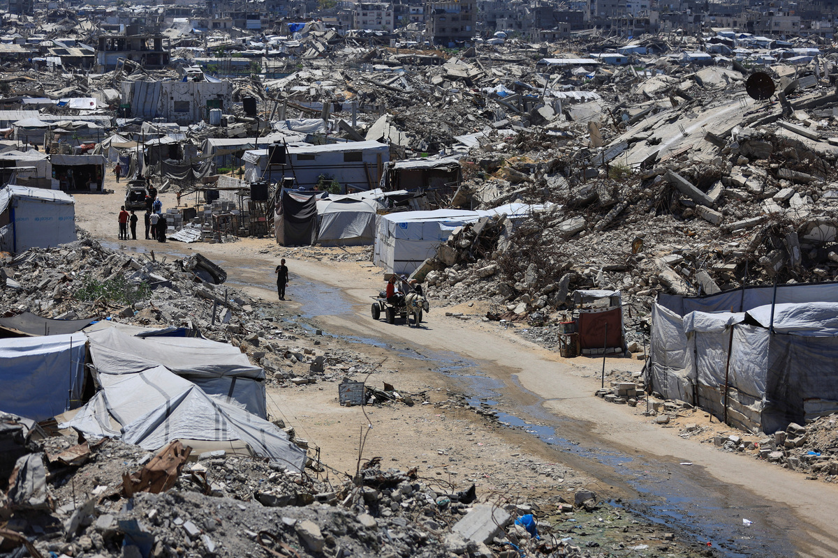 Palestinians make their way past the rubble of residential buildings destroyed during the Israeli offensive as displaced people shelter in tents, in Gaza City, June 15, 2026. REUTERS/Dawoud Abu Alkas