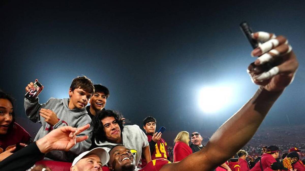  Nov 29, 2025; Los Angeles, California, USA; Southern California Trojans head coach Lincoln Riley (right) and defensive tackle Jahkeem Stewart (4) pose with fans after the game against the UCLA Bruins at United Airlines Field at Los Angeles Memorial Coliseum. Mandatory Credit: Kirby Lee-Imagn Images | Kirby Lee-Imagn Images 