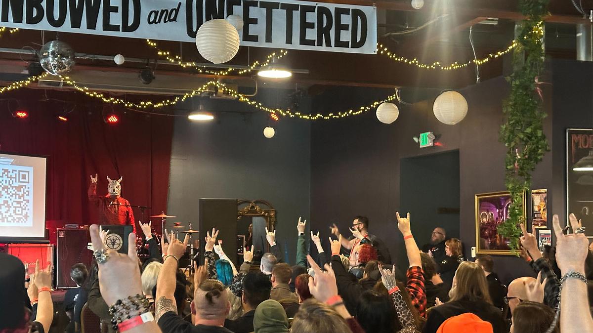 Satantic Temple members hold up a devil horn hand gesture as they chant “Hail Satan." (Bridget Byrnes/The Baltimore Sun/TNS)