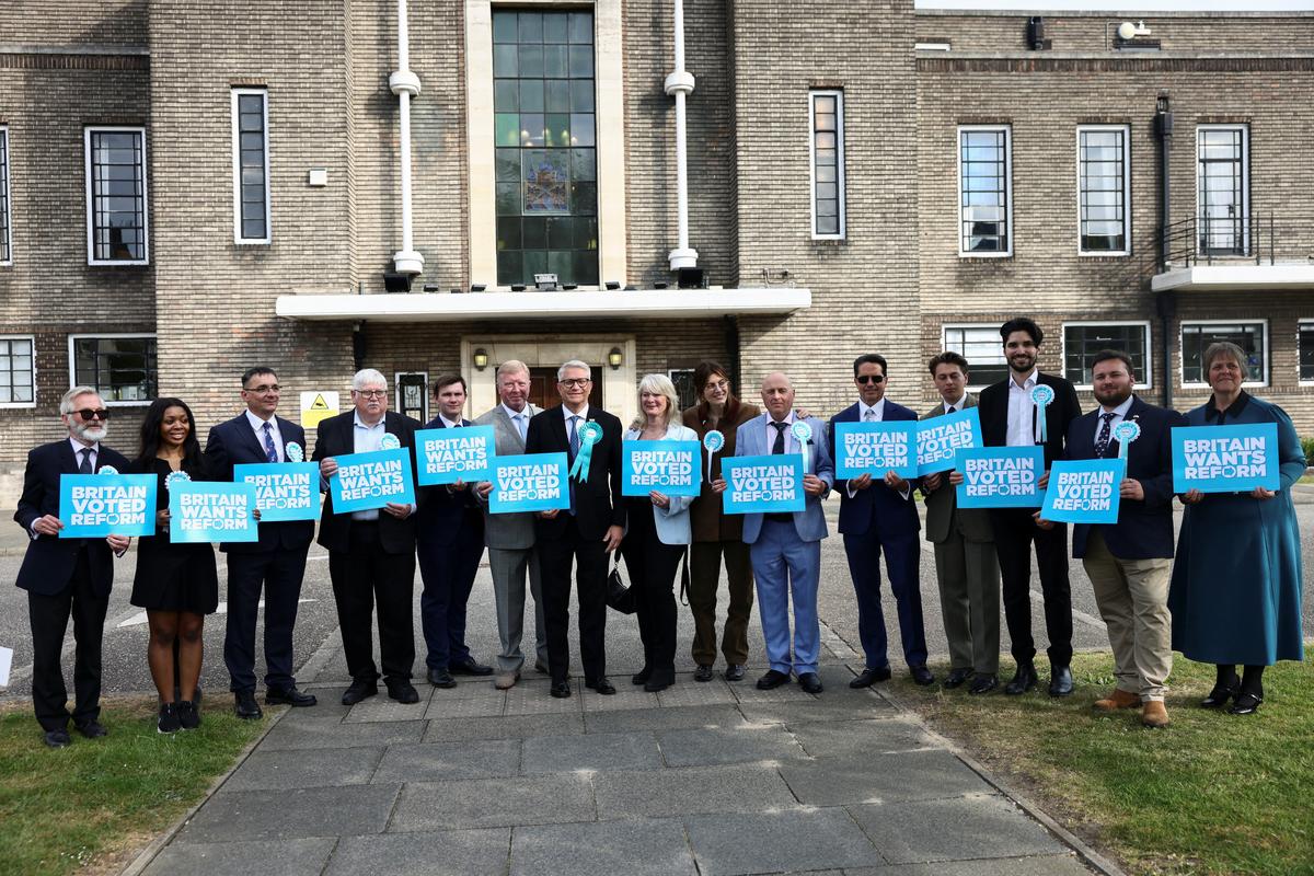 Newly elected councillors and Member of Parliament, Andrew Rosindell pose with signs at the Havering Town Hall, following the results of the local elections, in the London Borough of Havering, Britain, May 8, 2026. REUTERS/Jack Taylor