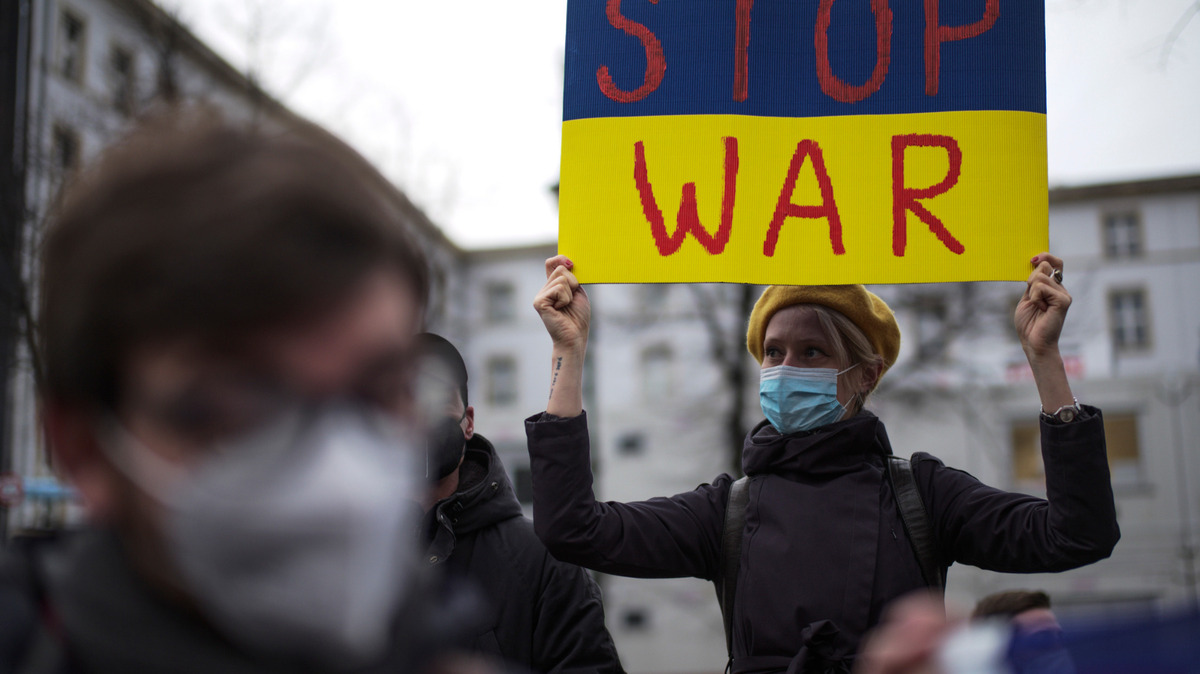 Una mujer con un cartel con los colores de la bandera ucraniana que dice “Alto a la guerra” asiste a una manifestación contra las tensiones entre Rusia y Ucrania, cerca de la embajada rusa en Berlín, Alemania, el martes 22 de febrero de 2022. (AP Foto/Markus Schreiber)