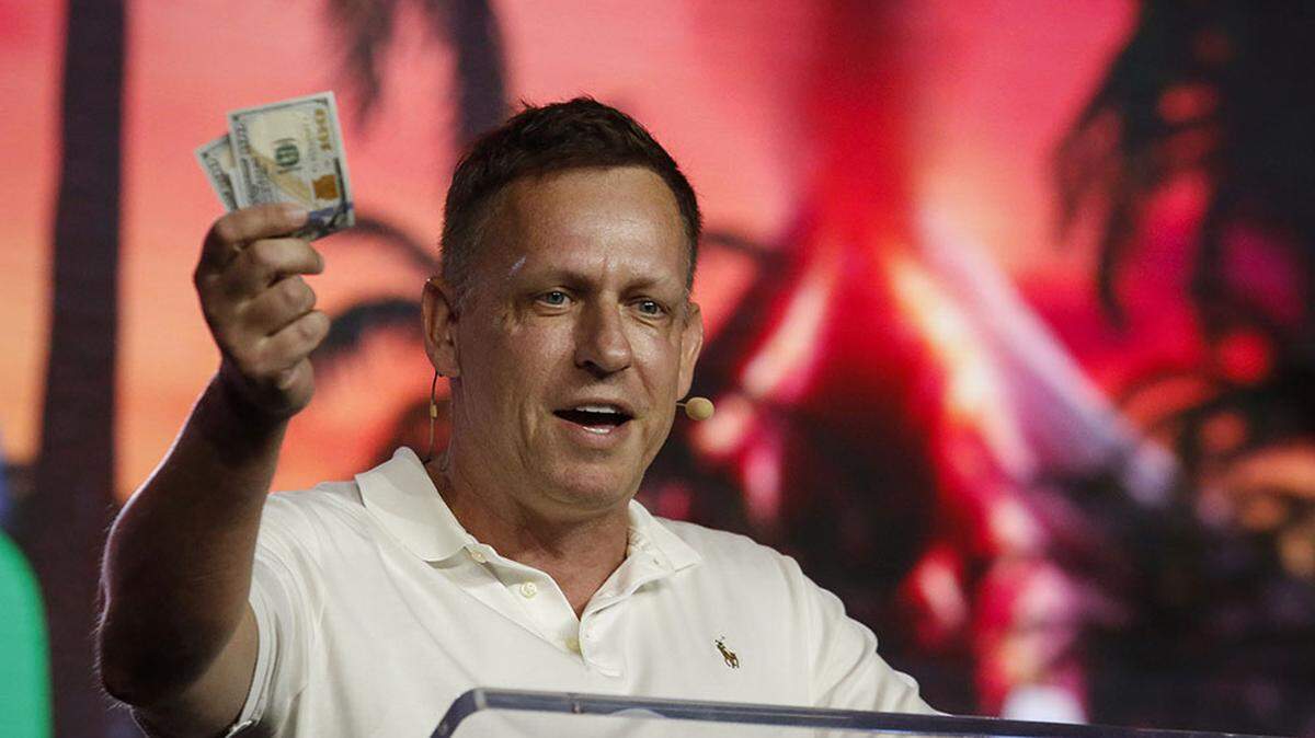 Peter Thiel, co-founder of PayPal, Palantir Technologies, and Founders Fund, holds hundred dollar bills as he speaks during the Bitcoin 2022 Conference at Miami Beach Convention Center on April 7, 2022, in Miami, Florida.
