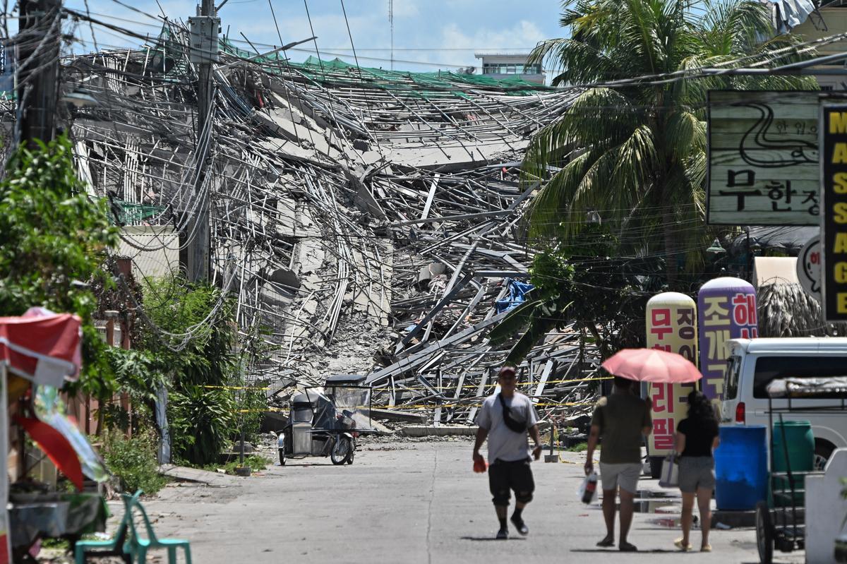 People walk near the nine-story building under construction that collapsed in Balibago, Angeles City, Pampanga, Philippines, May 24, 2026. REUTERS/Noel Celis