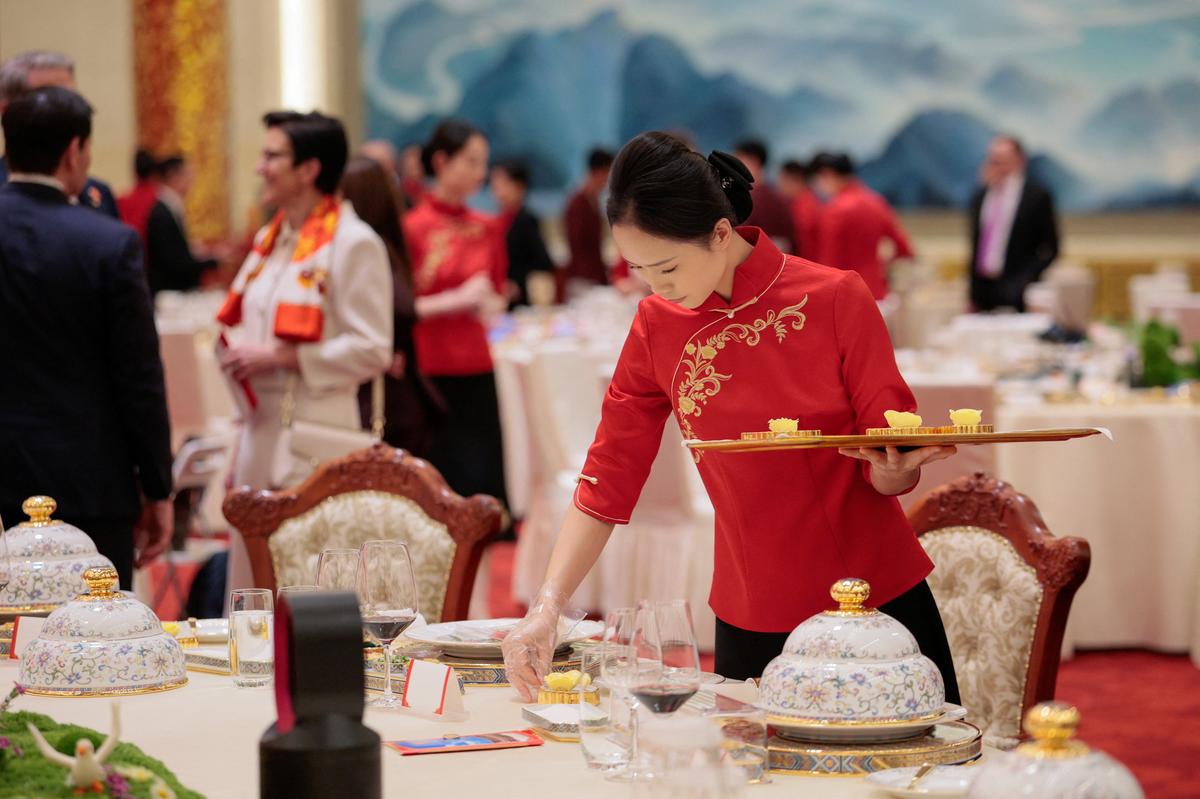 A worker prepares a place setting as attendees arrive for a state banquet with U.S. President Donald Trump and Chinese President Xi Jinping at the Great Hall of the People in Beijing, China, May 14, 2026. REUTERS/Evan Vucci