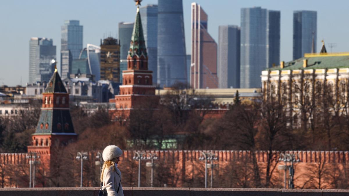 A woman walks along a bridge, with the Moscow City business centre and the Kremlin wall seen in the background, on a sunny day in Moscow, Russia, February 24, 2025. REUTERS/Evgenia Novozhenina/File Photo
