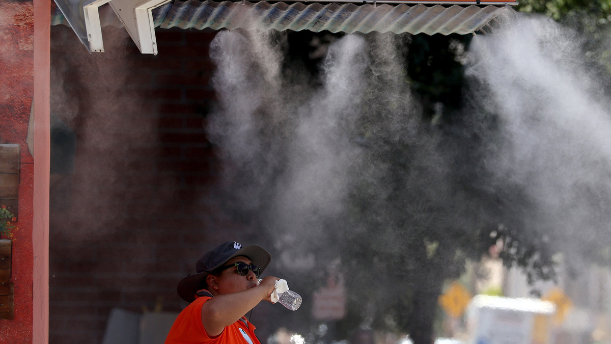 A Downtown Phoenix Ambassador takes a drink of water while cooling off under a mister on June 5, 2024, in Phoenix. (Justin Sullivan/Getty Images/TNS)