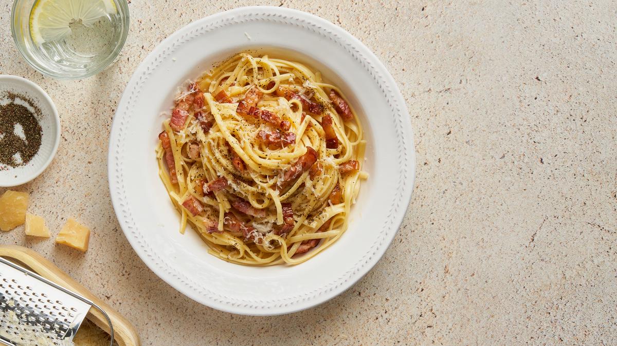 Carbonara pasta. Spaghetti with pancetta, egg, parmesan cheese and cream sauce. Traditional Italian cuisine. Top view, copy space
