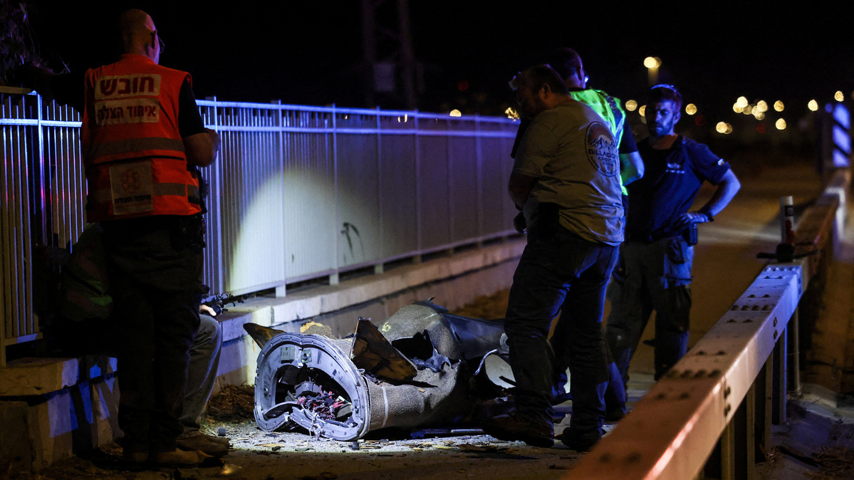 Israeli security and rescue personnel work next to a part of a projectile following a missile attack from Iran in northern Israel on Monday. Israel said it struck military targets in western and central Iran on Monday, a day after Tehran launched a barrage of missiles at Israel for its continuing attacks on Beirut.