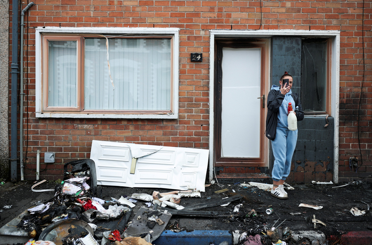 A resident takes pictures of debris on a street in the neighbourhood, in the aftermath of anti-immigrant protests following a knife attack on June 8, which left a man seriously injured and prompted police to declare a critical incident, at Lendrick Street, east Belfast, Northern Ireland, June 10, 2026. REUTERS/Isabel Infantes