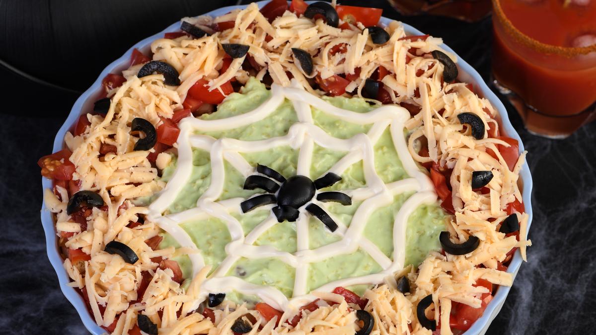 Spooky Halloween Seven Layer Taco Dip Turn a classic appetizer into a Halloween favorite with just a little sour cream artistry and a of black olive spiders.
