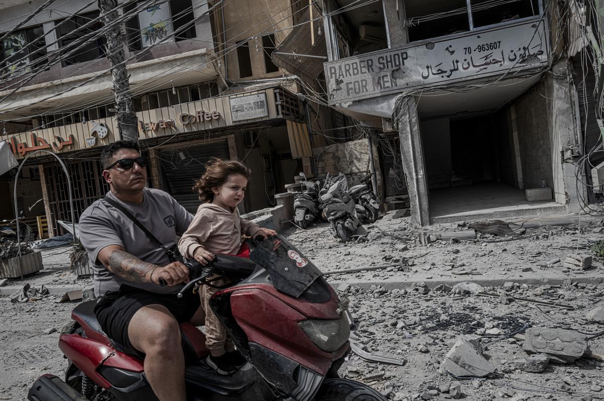 A man and his daughter maneuver through debris covering the main road after recent Israeli strikes in Tyre, Lebanon, May 29, 2026. (Daniel Berehulak/The New York Times)
