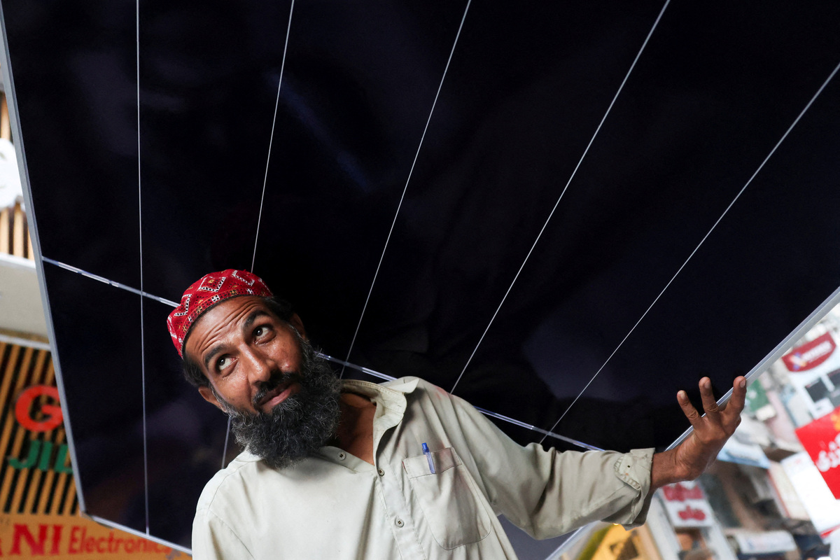 FILE PHOTO: A worker carries a solar panel sheet on his head to load it on a vehicle outside a shop at an electronic items market in Karachi, Pakistan June 3, 2026. REUTERS/Akhtar Soomro/File Photo