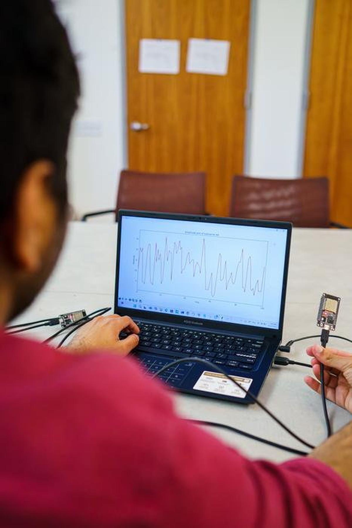 Computer Science and Engineering Ph.D. student Nayan Bhatia demonstrates Pulse-Fi, a technology that uses WiFi signals to measure a person's heart rate. (Erika Cardema/UC Santa Cruz via SWNS) 