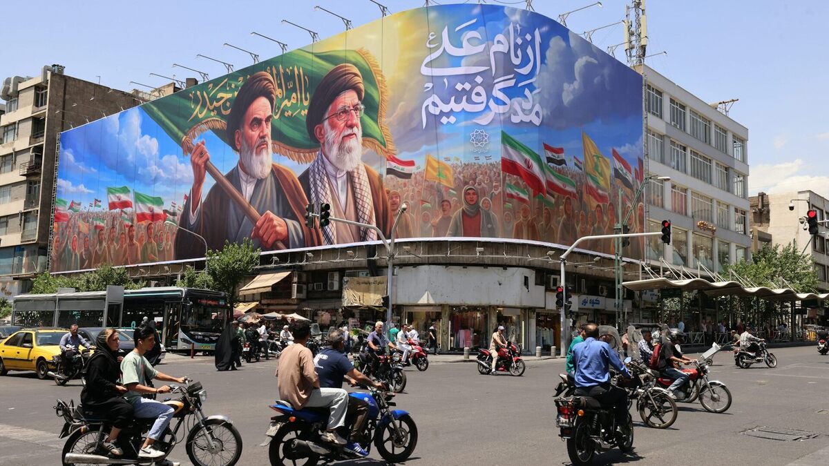 People ride motorcycles past a large billboard in central Tehran on June 8, 2026. 