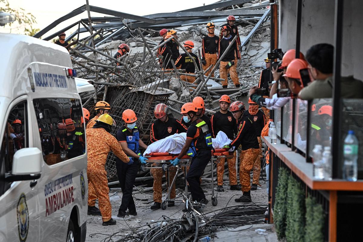 Rescue workers retrieve the body of a victim among debris as a nine-story building under construction collapsed in Balibago, Angeles City, Pampanga, Philippines, May 24, 2026. REUTERS/Noel Celis