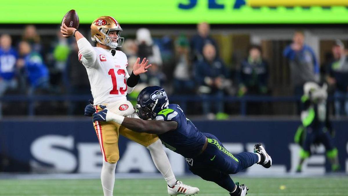  Jan 17, 2026; Seattle, WA, USA; San Francisco 49ers quarterback Brock Purdy (13) is pressured by Seattle Seahawks defensive end DeMarcus Lawrence (0) during the first half in an NFC Divisional Round game at Lumen Field. Mandatory Credit: Steven Bisig-Imagn Images | Steven Bisig-Imagn Images 