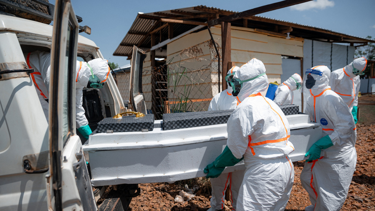 Volunteers of the Democratic Republic of Congo Red Cross wearing personal protective equipment load the casket containing the body of an Ebola victim at the morgue of the Rwampara health center. Officials on Tuesday said that the number of confirmed deaths linked to the Ebola outbreak in the DRC has risen to 102.