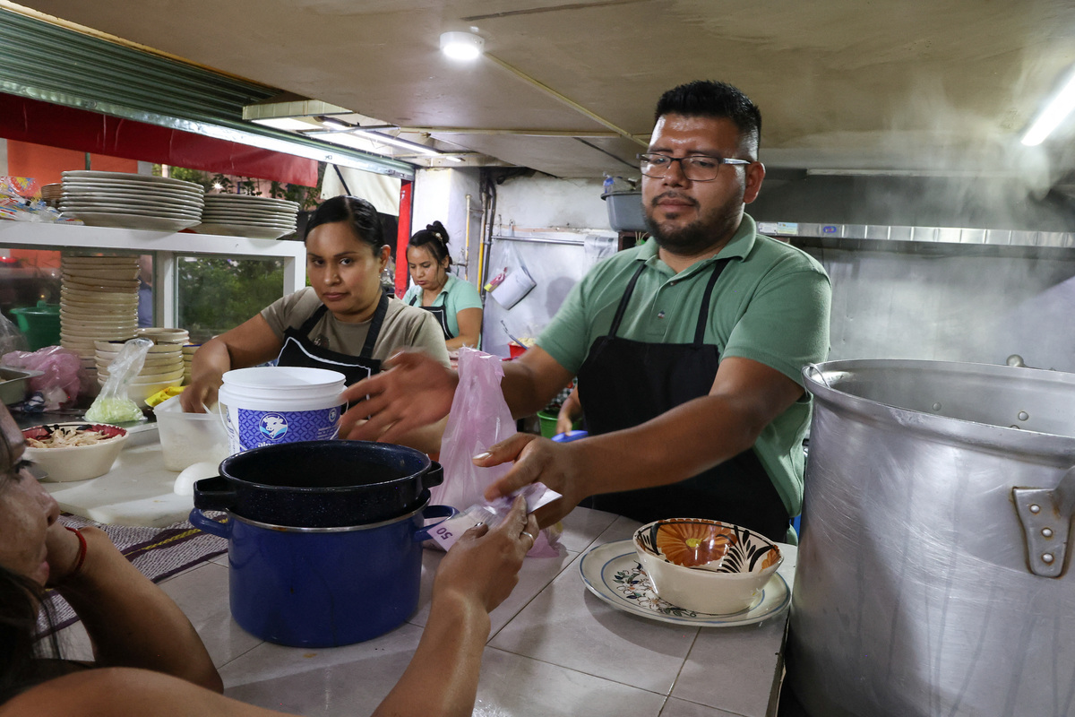 Julio Mendoza, manager of the Las Delicias de la Obrera pozoleria restaurant, attends to a client, as many Mexicans say they feel excluded from the 2026 FIFA World Cup despite the tournament's return to the country, citing high ticket prices, paid television access and strict commercial restrictions, while the restaurant cannot afford a special package to show the games, in Mexico City, Mexico, June 13, 2026. REUTERS/Diego Delgado