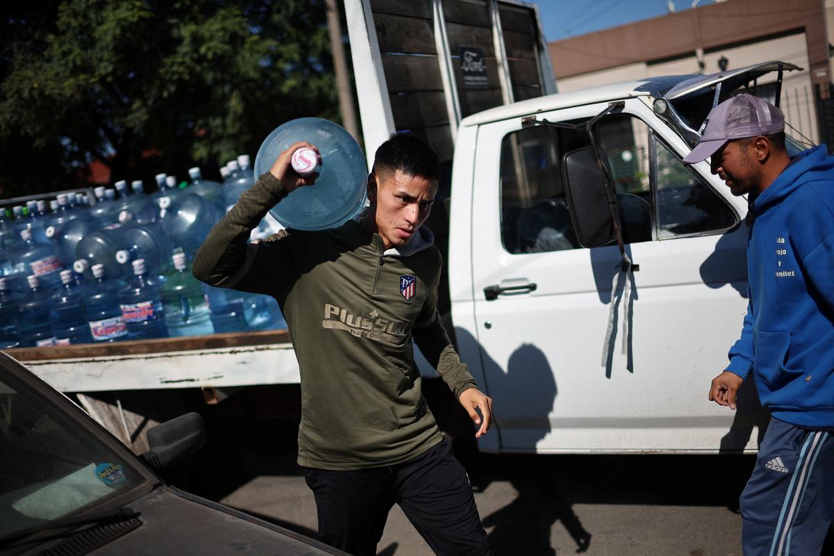 Emiliano Migueles, 26, carries a large water container as he delivers bottled water from a truck, with his uncle Julian Trejo, during his workday in Merlo, on the outskirts of Buenos Aires, Argentina, April 10, 2026. Migueles delivers bottled water alongside his uncle from a dilapidated truck, a precarious job with a fluctuating income. Over half of Argentinians under the age of 30 are employed in the informal economy, according to 2025 data from state statistics agency INDEC. REUTERS/Agustin Marcarian SEARCH "MARCARIAN ARGENTINA POTRERO" FOR THIS STORY. SEARCH "WIDER IMAGE" FOR ALL STORIES.