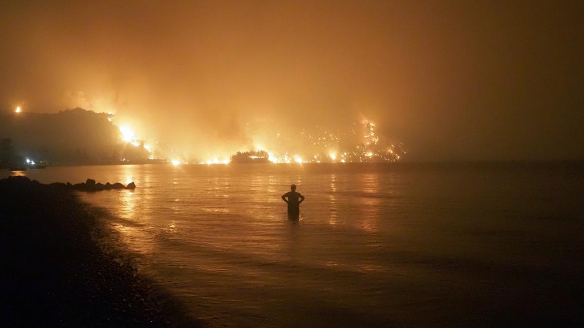 En esta foto del viernes 6 de agosto de 2021, un hombre observa cómo un incendio se acerca a una playa en el pueblo de Limni, en la isla Evia, a 100 millas al norte de Atenas, Grecia. Un reporte científico de las Naciones Unidas advierte del impacto negativo que han tenido las actividades humanas en el planeta.