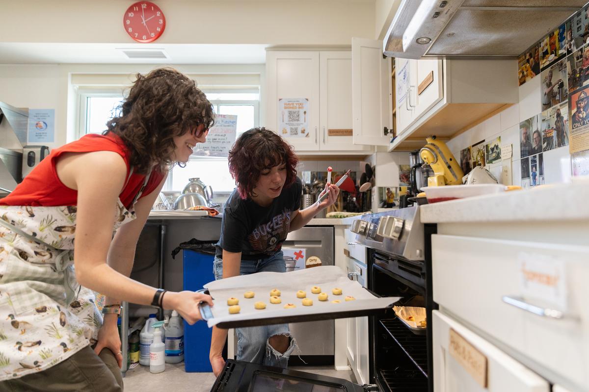 Annie Rogovin, left, and Maya Allen tending to Rogovin's butter cookies at the Dacie Moses House, Carleton College's cookie house in Northfield, Minn., March 30, 2026. For decades, Carleton College has kept a place where students and others can come, bake and share. (Liam James Doyle/The New York Times)