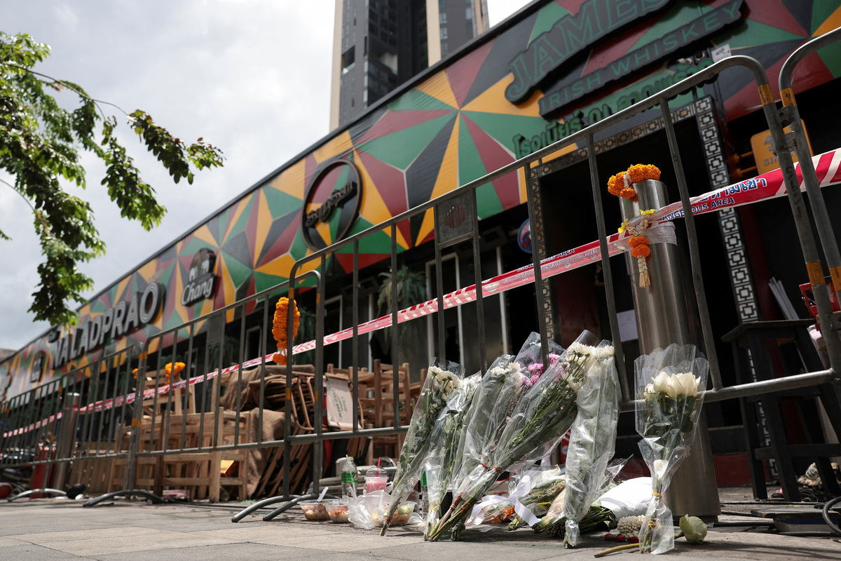 Flowers and offerings are placed outside Rong Beer Na Lat Phrao bar, the site of a deadly fire, to pay tribute to victims who lost their lives in the bar fire, the day after the incident, in Bangkok, Thailand, July 14, 2026. REUTERS/Chalinee Thirasupa