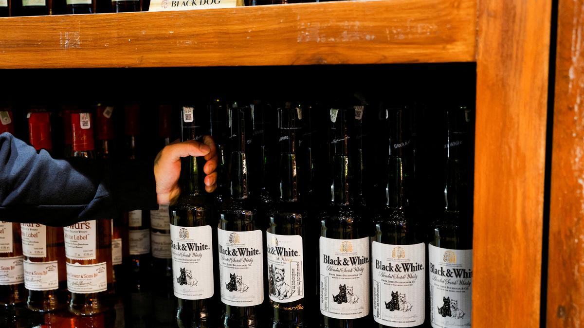 FILE PHOTO: A salesman picks a bottle of Black & White blended Scotch whisky, a brand of Diageo’s United Spirits Ltd, from a shelf at a liquor store in Bengaluru, India, January 20, 2026. REUTERS/Priyanshu Singh/File Photo