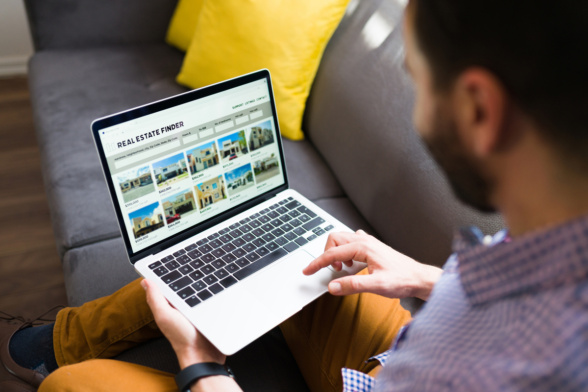  A stock photo of a man looking at homes on a real estate website on a laptop computer. 