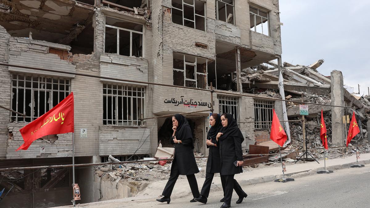 Iranian women walk past a residential building destroyed in a U.S.-Israeli airstrike, in Tehran, Iran, on Monday, April 13, 2026. (-/AFP/Getty Images/TNS)