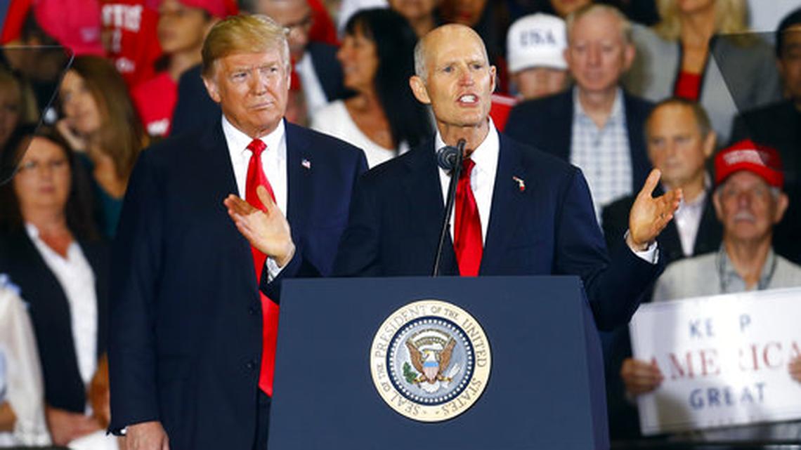 FILE- In this Nov. 3, 2018, file photo President Donald Trump stands behind Florida Gov. Rick Scott as he speaks at a rally in Pensacola, Fla. Scott defeated U.S. Senator Bill Nelson. The senatorial race is one of the top stories in Florida in 2018.