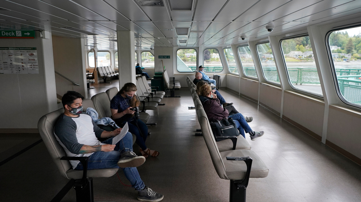 Omar Rodas, left, reads information about the Pfizer COVID-19 vaccine after he received the first shot of it, Tuesday, May 25, 2021, while sailing on a Washington state ferry from Bremerton, Wash. to Seattle. Tuesday was the first day of several dates that the vaccine would be offered to people on ferry sailings between the two cities. (AP Photo/Ted S. Warren)