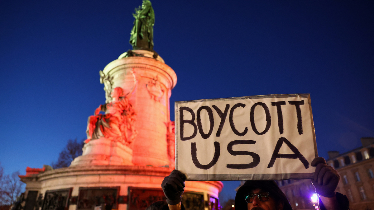 A man holds up 'Boycott USA' sign, as people demonstrate to oppose U.S. actions in Venezuela at a protest, after U.S. President Donald Trump said the U.S. has struck Venezuela and captured its President Nicolas Maduro, in Paris, France, January 3, 2026. REUTERS/Abdul Saboor