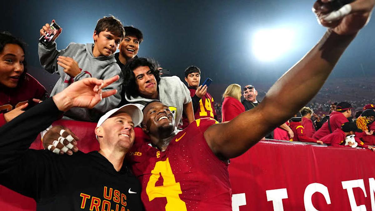  Nov 29, 2025; Los Angeles, California, USA; Southern California Trojans head coach Lincoln Riley (right) and defensive tackle Jahkeem Stewart (4) pose with fans after the game against the UCLA Bruins at United Airlines Field at Los Angeles Memorial Coliseum. Mandatory Credit: Kirby Lee-Imagn Images | Kirby Lee-Imagn Images 