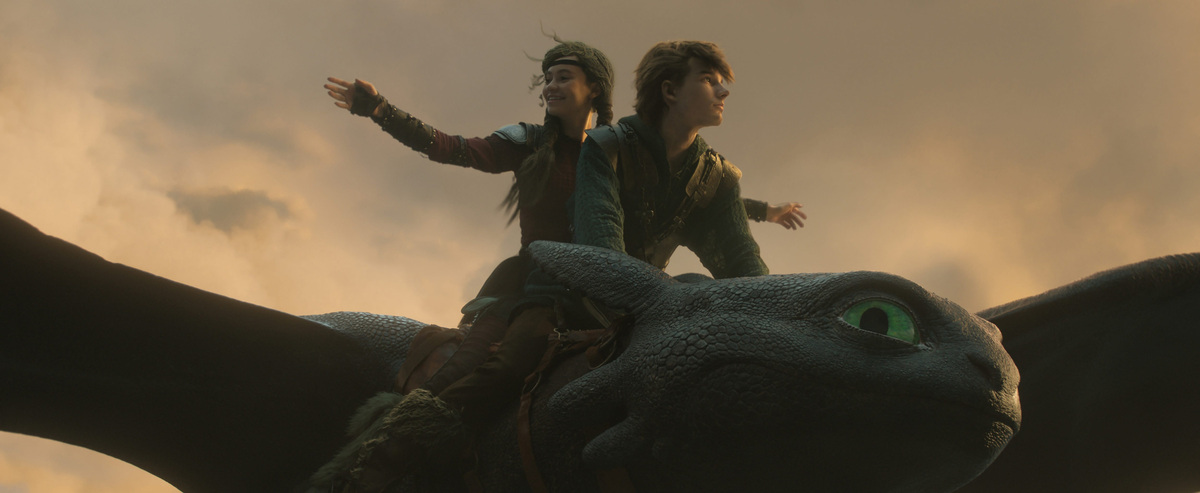 Astrid (Nico Parker) and Hiccup (Mason Thames) ride high with their Night Fury friend Toothless in the live-action "How to Train Your Dragon."