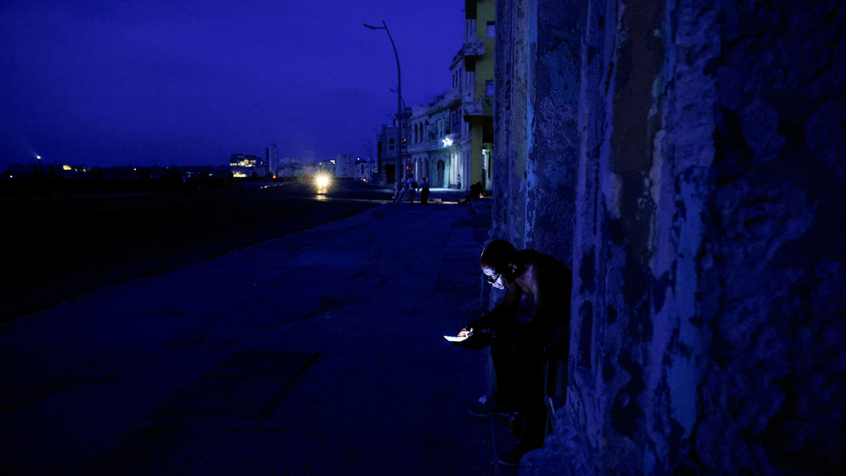 A man checks his phone outdoors as Cuba's national electric grid collapsed at midday, leaving around 10 million people without power, in Havana, Cuba, July 6, 2026. REUTERS/Norlys Perez