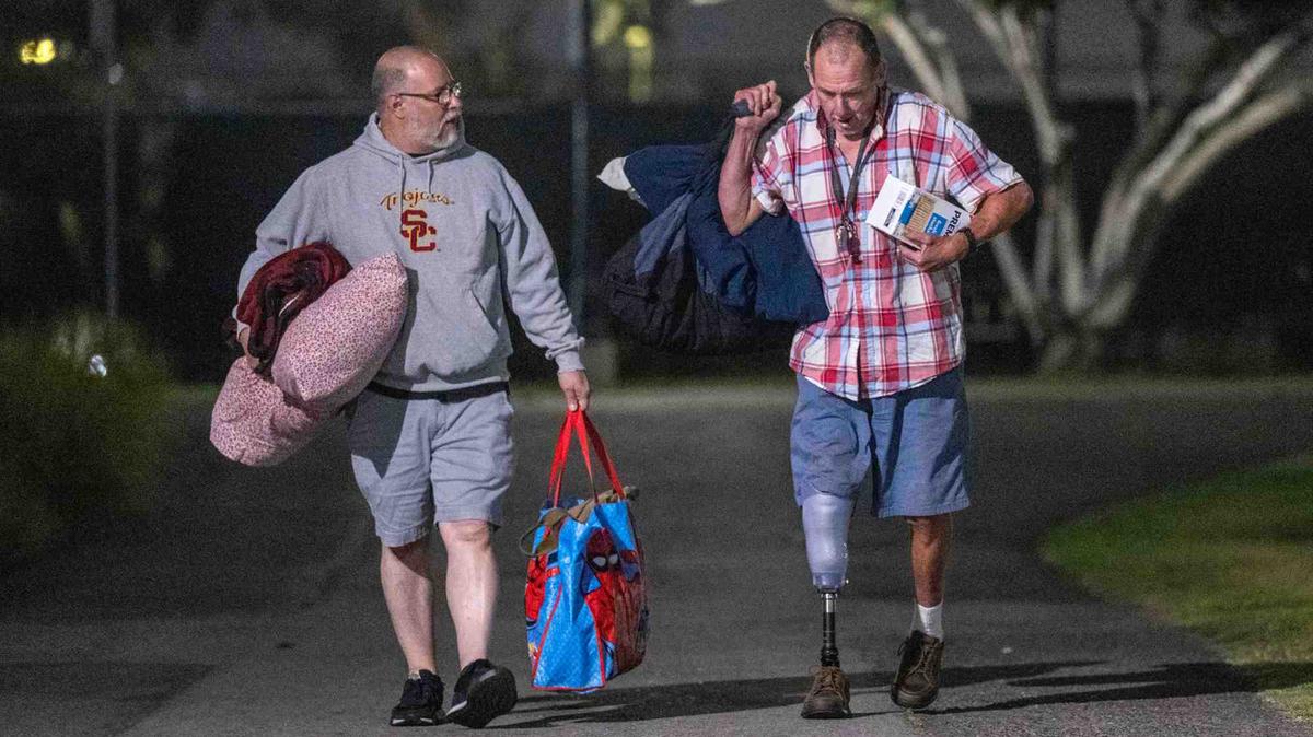 Tom Hanson, right, of Westminster and Rodrigo Garay of Garden Grove walk together as they arrive at a temporary shelter at Golden West College, one of several evacuation sites from an ongoing hazmat incident at GKN Aerospace in Garden Grove, in Huntington Beach, Calif., on Saturday, May 23, 2026. Garay, left, who lives just a few blocks from the epicenter of the evacuation zone, helped Hanson, who is walking on a brand new prosthetic leg that he got this week, as they arrive at the shelter at the same time Saturday night. (Jeff Antenore/The Orange County Register/TNS)