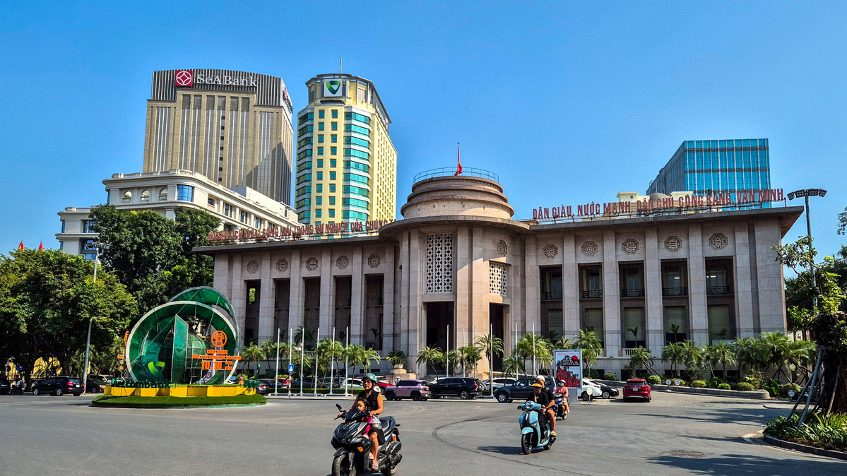People ride motorcycles in front of the headquarter of the State Bank of Vietnam in Hanoi, Vietnam, November 19, 2024. REUTERS/Khanh Vu